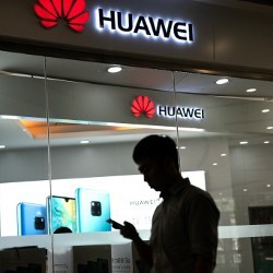 man walks past Huawei store in Beijing