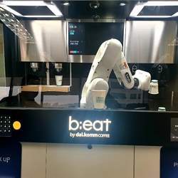 A b;eat robot barista making coffee at a Dal.Komm Coffee franchise.