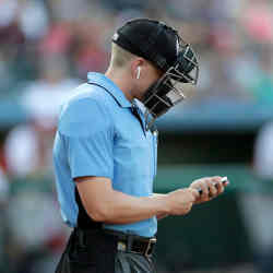 Home plate umpire Brian deBrauwere checks an iPhone while wearing an earpiece prior to the start of the Atlantic League All-Star Game.