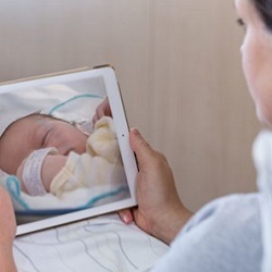 woman looking at a computer tablet with a baby on the screen