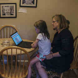 A mother plays educational games on the computer with her daughter. 