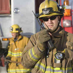 A firefigher uses a walkie-talkie during a disaster.