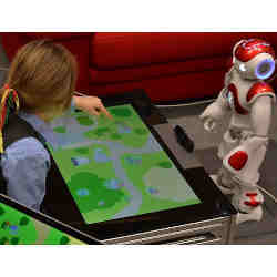 A child interacts with the robot tutor while a teacher provides guidance to the robot