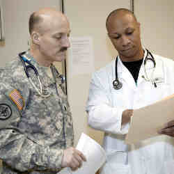 Military doctors consult over a patient's chart.