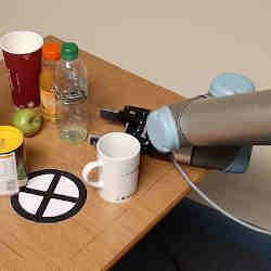 A robot arm attempts to clear a cluttered table.