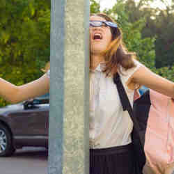 An inattentive girl walking, distracted by her mobile phone, crashed into street post.