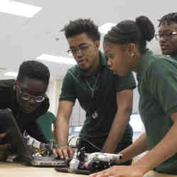 High school students adjust a robot's programming.