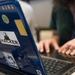 user at laptop computer with hacker sticker