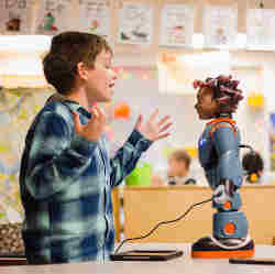 A boy interacts with robot Milo, which was designed to teach students with autism to tune in to emotions, express empathy and better understand social situations. 