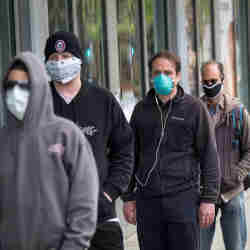 Customers wearing protective masks wait in a line outside a Whole Foods Market store in San Francisco.