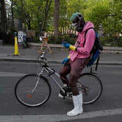 A delivery man in Paris wearing protective gear and checking his phone. 