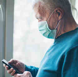 A man wearing a medical mask and reading his phone.