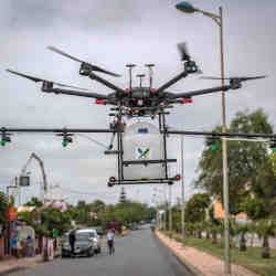 A drone equipped with disinfectant liquid flies above a Morocco street.