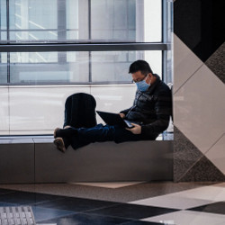 young man wearing mask using laptop computer