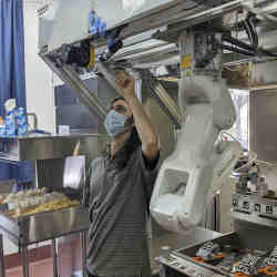 A technician makes an adjustment to a robot at Miso Robotics' White Castle test kitchen in Pasadena, CA.