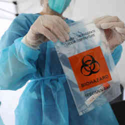 A medical professional seals coronavirus test material in a specimen bag.