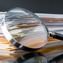 magnifying glass and a stack of papers