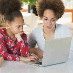 A woman helps her daughter with homework.