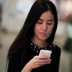 A young woman reading her phone.