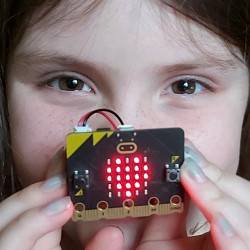 girl holding micro:bit circuit board in front of her face