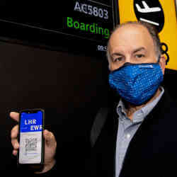 Peter Vlitas, a travel industry executive, holding up the health passport app CommonPass. 