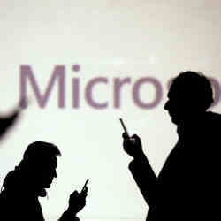 User silhouettes in front of a Microsoft sign. 