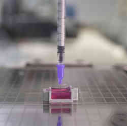 A syringe in a 3d printer extruding ink into a special gel bath.