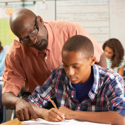 teacher pointing at work over shoulder of male student