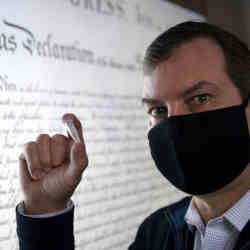 The University of California Irvine's Steve Zylius with a vial of TNA, in front of the Declaration of Independence.