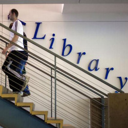 man walking up stairs in library