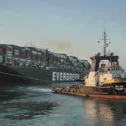 A tugboat helps dislodge the shipping vessel Evergreen from the Suez Canal..