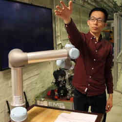 KTH researcher Hongyi Liu tests a robot arm by placing his hand in its path.