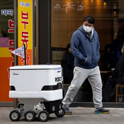 man looking at robot on sidewalk