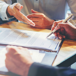 arms and hands of two men in business attire at a desk