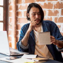 worker at laptop computer looking at notebook