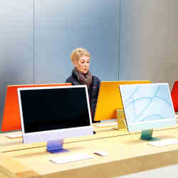 A woman examines a display of Macs. 