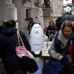 Pedestrians pass a Knightscope Inc. K5 security robot on Wall Street near the New York Stock Exchange.