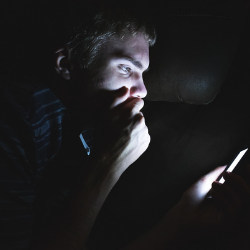 man looking at mobile phone in the dark