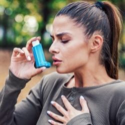 Woman holding chest having trouble breathing and using an inhaler