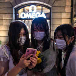 Three Chinese women share a smartphone screen.