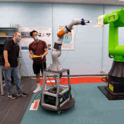 University of Cincinnati graduate students Andrew Barth (left) and Yufeng Sun with the furniture-moving robots.