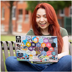 Amelia Hernandez sits on the ECU campus with her laptop computer