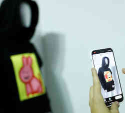 A woman uses her smartphone to see a virtual animation on partially virtual clothing.