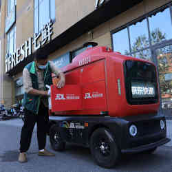 An employee of the 7Fresh supermarket loads goods on a JD Logistics autonomous delivery vehicle in Beijing, China
