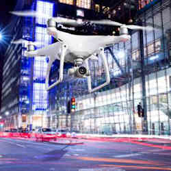 An aerial drone snaps photos of a London street at night. 