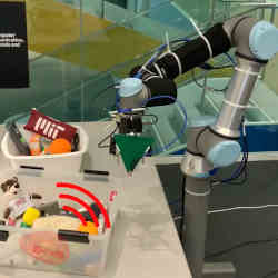 The robotic arm (right) seeks keys with an RF tag affixed, hidden beneath other items.