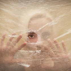 Woman looking through a hole cut into a sheet of plastic