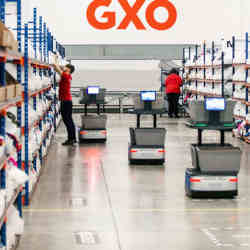 Staff and collaborative robots work together in a GXO Logistics warehouse.