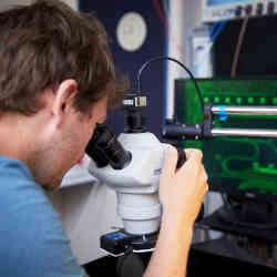 A Toshiba scientist examines a quantum key distribution chip under the microscope.