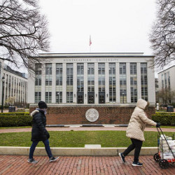 two people walking by Northeastern University's Ell Hall